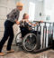 Een vrouw helpt een persoon in een rolstoel met een lift de trap op te gaan